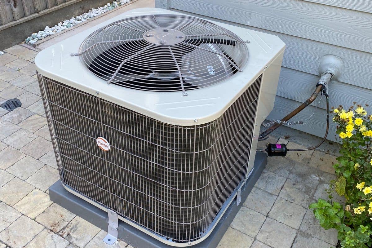Complete residential air conditioning condenser unit installed on a level pad beside a home
